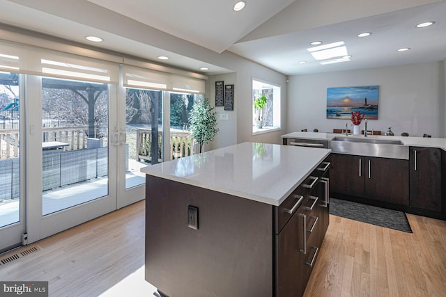 kitchen featuring a sink, a kitchen island, vaulted ceiling, and light wood finished floors