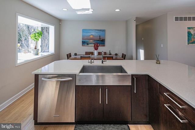 kitchen featuring visible vents, a sink, light countertops, stainless steel dishwasher, and light wood-type flooring