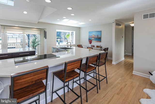 kitchen with visible vents, light wood-type flooring, a sink, recessed lighting, and black electric stovetop