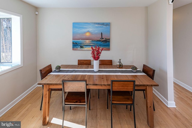 dining space with baseboards and wood finished floors