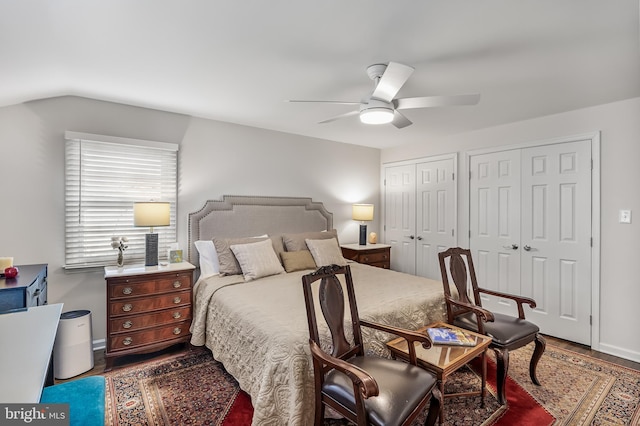 bedroom featuring baseboards, wood finished floors, multiple closets, and ceiling fan