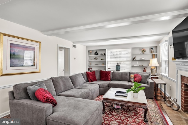 living area featuring visible vents, built in shelves, baseboards, beam ceiling, and a fireplace