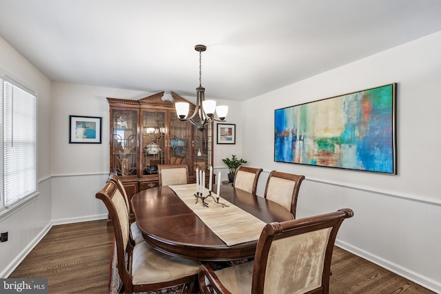 dining area featuring dark wood finished floors, a notable chandelier, and baseboards