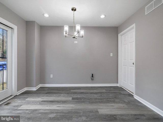 spare room featuring a notable chandelier, visible vents, baseboards, and wood finished floors