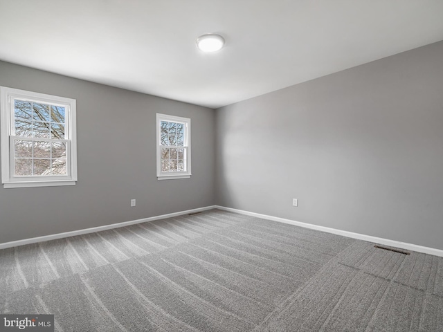 carpeted spare room with visible vents and baseboards