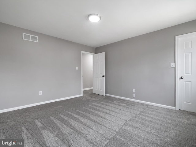 unfurnished room featuring baseboards, visible vents, and dark carpet