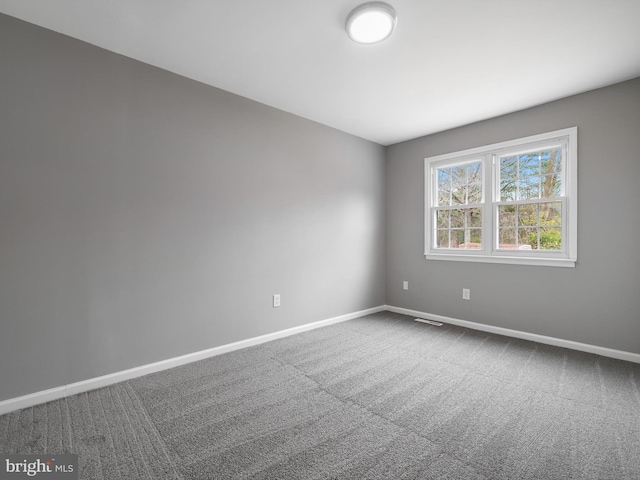 carpeted empty room featuring visible vents and baseboards