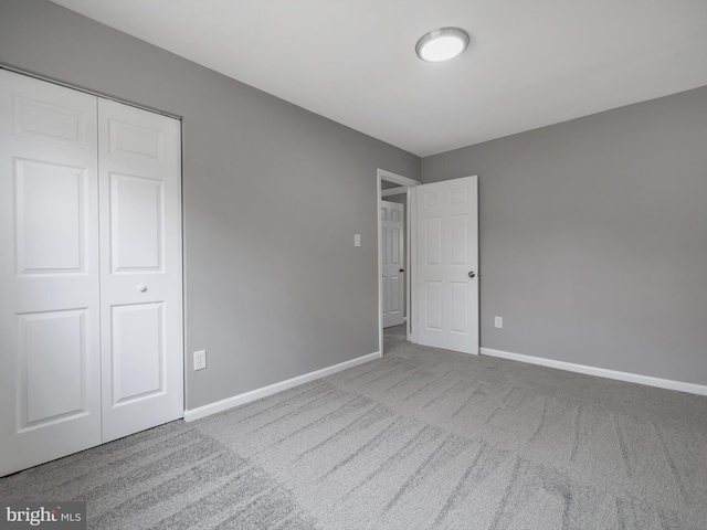 unfurnished bedroom with a closet, baseboards, and carpet flooring