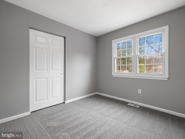 unfurnished bedroom featuring carpet flooring, baseboards, visible vents, and a closet