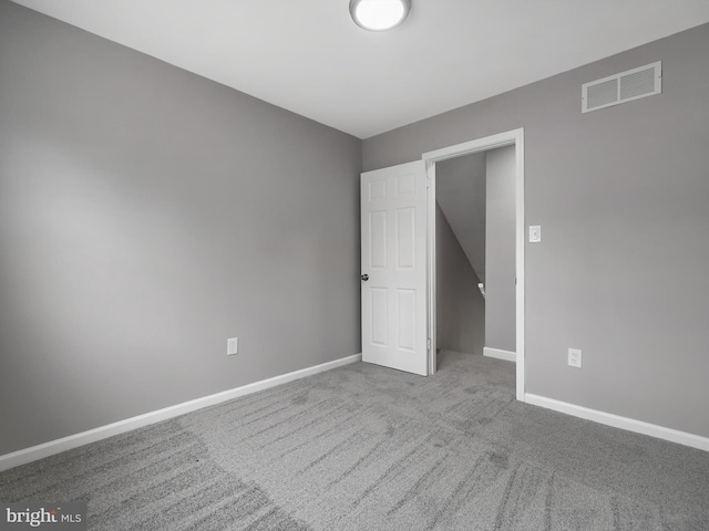 carpeted spare room featuring visible vents and baseboards