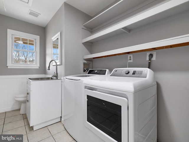 clothes washing area featuring visible vents, a sink, washing machine and dryer, light tile patterned floors, and laundry area