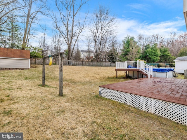 view of yard featuring an outbuilding, a storage unit, a fenced backyard, and a wooden deck