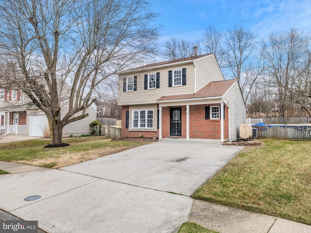 colonial inspired home with brick siding, driveway, a chimney, and a front lawn