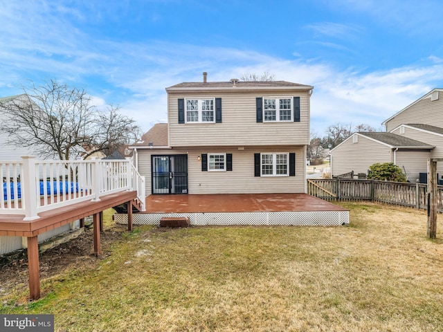 rear view of property featuring a lawn, a shingled roof, a deck, and fence