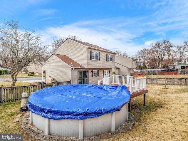 back of house with a fenced in pool, a lawn, a deck, and fence