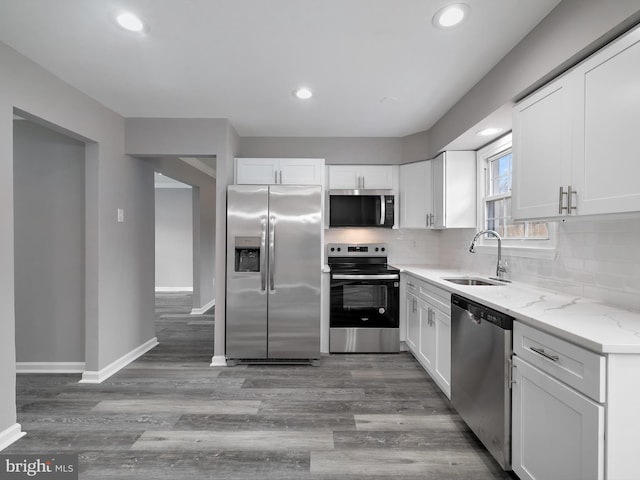 kitchen with light wood finished floors, a sink, white cabinets, appliances with stainless steel finishes, and tasteful backsplash