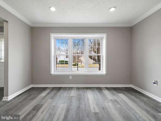 unfurnished room featuring wood finished floors, visible vents, baseboards, ornamental molding, and a textured ceiling