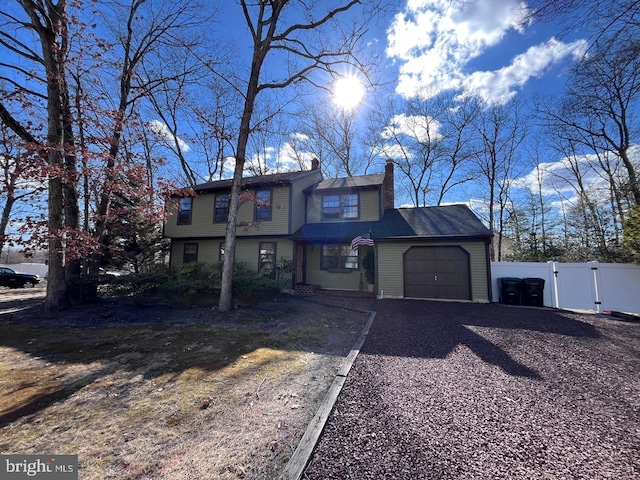 view of front of property with a gate, fence, driveway, a chimney, and a garage