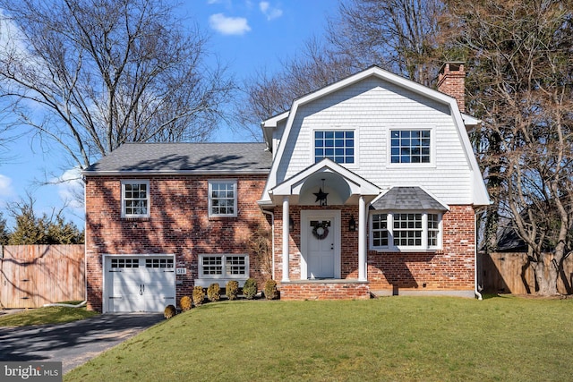 view of front of house with a gambrel roof, driveway, a chimney, and fence