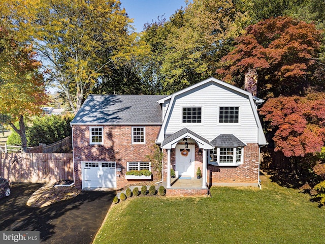 view of front of home featuring a gambrel roof, a front lawn, fence, a garage, and brick siding