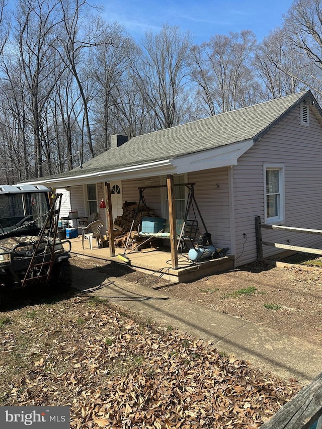 view of side of home featuring a chimney and roof with shingles