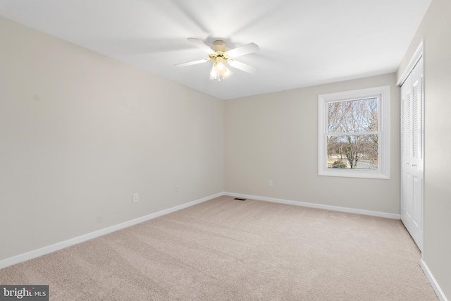 unfurnished bedroom featuring visible vents, light carpet, a ceiling fan, a closet, and baseboards