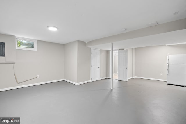 finished basement with baseboards and freestanding refrigerator