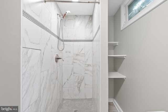 full bath featuring a tile shower and baseboards