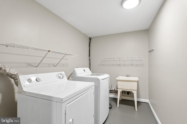 laundry area with washing machine and clothes dryer, laundry area, baseboards, and a sink