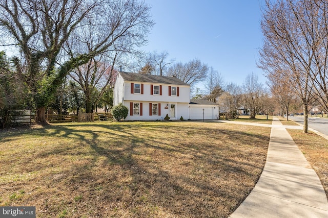 colonial house featuring a garage, concrete driveway, a front lawn, and fence