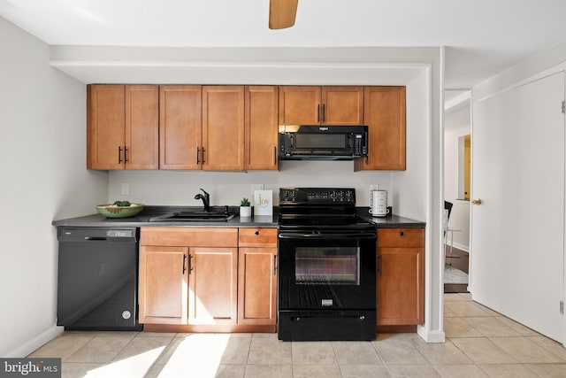 kitchen featuring brown cabinetry, light tile patterned flooring, a sink, black appliances, and dark countertops