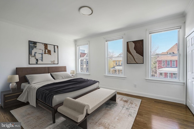 bedroom featuring multiple windows, crown molding, dark wood-type flooring, and baseboards