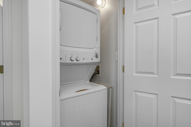 clothes washing area with stacked washer and clothes dryer and laundry area