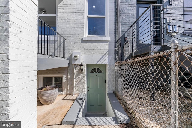 property entrance with a balcony and brick siding