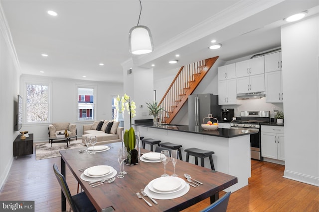 dining space featuring light wood finished floors, crown molding, baseboards, stairway, and recessed lighting