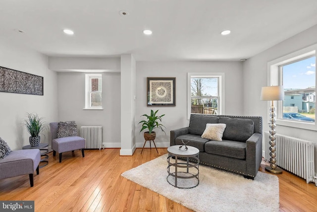 living room with light wood finished floors, recessed lighting, radiator, and baseboards