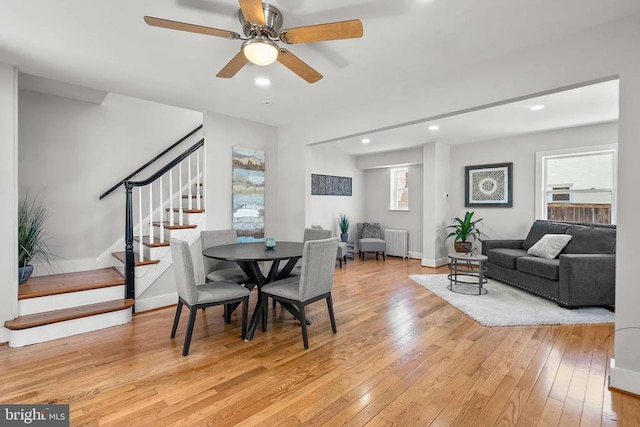 dining area featuring stairway, radiator heating unit, a healthy amount of sunlight, and light wood-type flooring