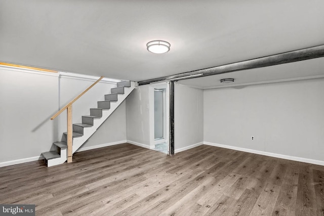 finished basement with baseboards, wood finished floors, and stairs