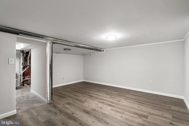 finished below grade area featuring baseboards, wood finished floors, and crown molding