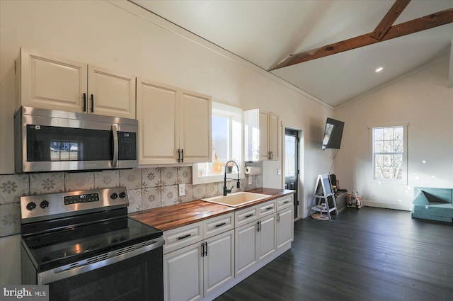 kitchen with vaulted ceiling with beams, decorative backsplash, appliances with stainless steel finishes, wood counters, and a sink