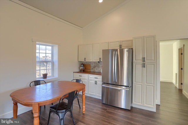 kitchen with crown molding, decorative backsplash, freestanding refrigerator, white cabinetry, and dark wood-style flooring