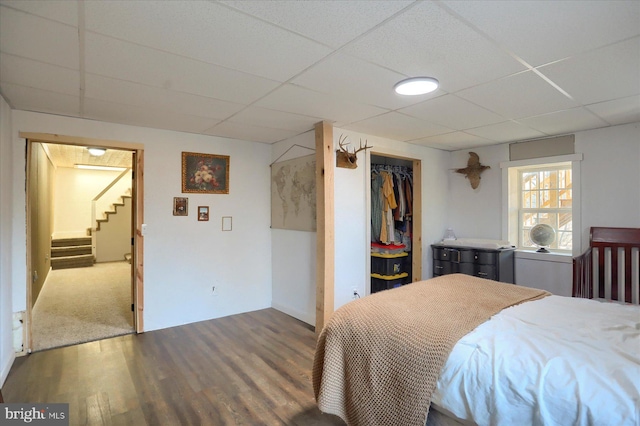 bedroom with wood finished floors, a closet, and a drop ceiling