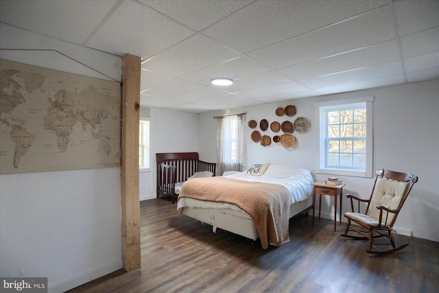 bedroom featuring a paneled ceiling, baseboards, and wood finished floors