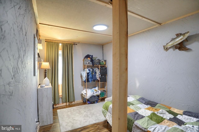 bedroom featuring a textured wall and wood finished floors