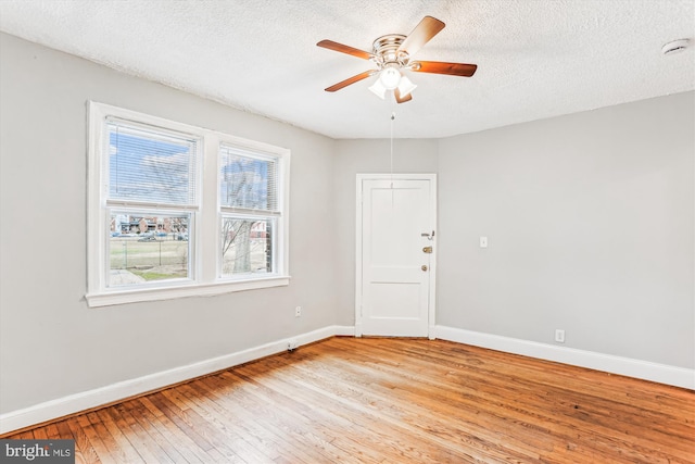 unfurnished room with light wood-type flooring, baseboards, a textured ceiling, and ceiling fan