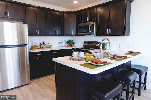 kitchen featuring a breakfast bar, light countertops, light wood-style floors, and stainless steel appliances