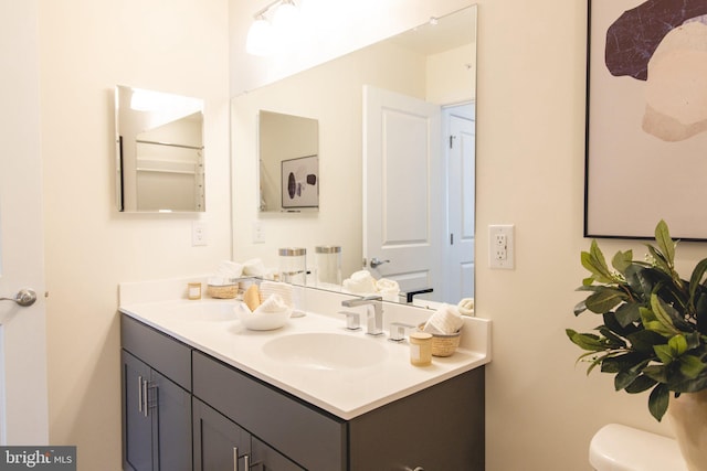 bathroom with double vanity, toilet, and a sink