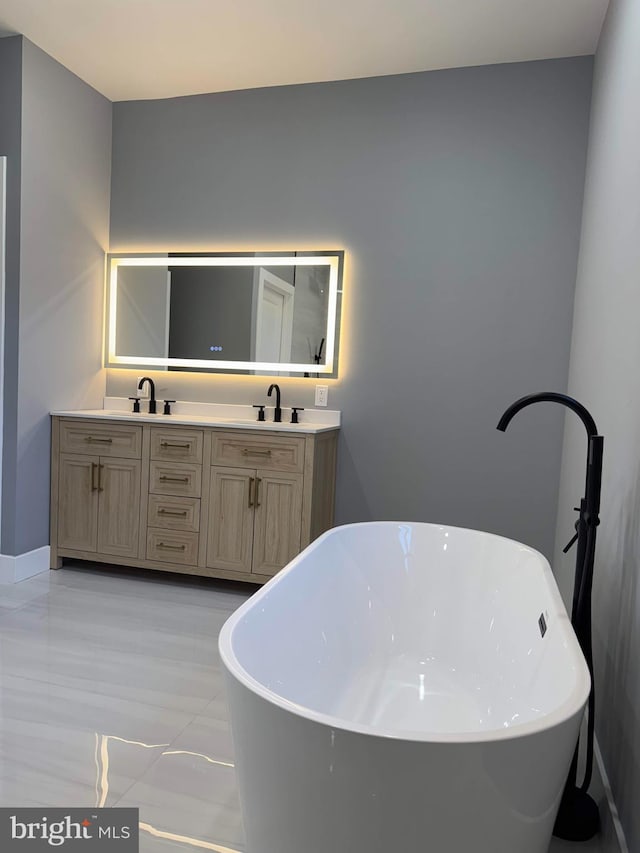 full bathroom featuring double vanity, a freestanding tub, and a sink