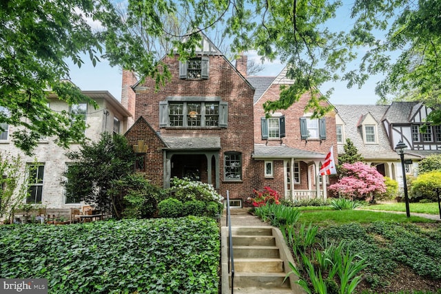 view of front facade featuring a chimney and brick siding