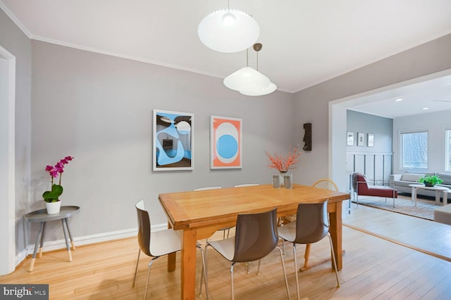 dining area with light wood-type flooring, ornamental molding, and baseboards